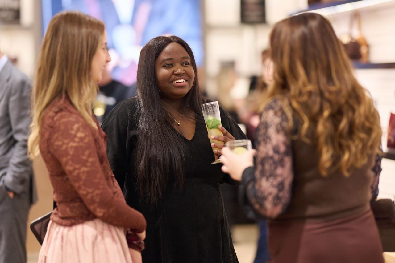 Tofunmi Balogun in a black dress, smiling mid-conversation at an industry event